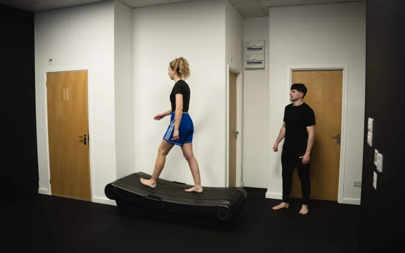 A Bristol Biomechanics coach observing a client's gait cycle on a treadmill during an assessment